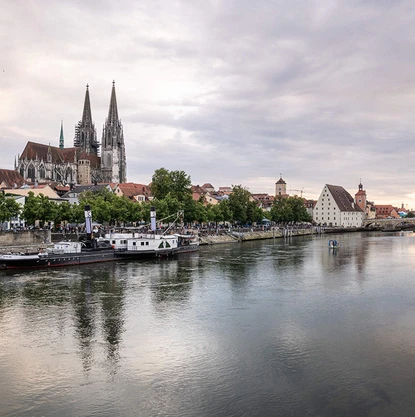 Man blickt über die Donau auf das andere Ufer. Der Dom ragt im Hintergrund auf.